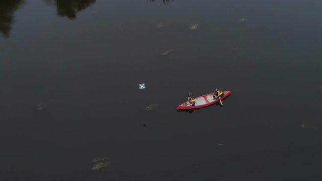 Aerial view of the two people on the paddleboat paddling their way on the river using the red boat in Ireland