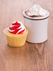 Strawberry cupcake with a cup of hot chocolate on dark wooden tabletop - anniversary or Valentine's treat to a loved one