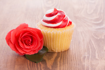 Strawberry cupcake with a beautiful red rose on wooden table, a simple treat to a loved one