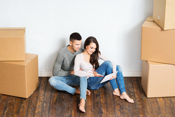 Couple sitting on the floor next to cardboard boxes