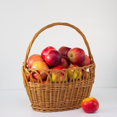 the whole fresh red apples in a wicker basket on a white background