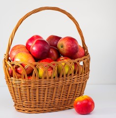 the whole fresh red apples in a wicker basket on a white background