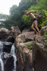 a man jumping off a cliff into the water