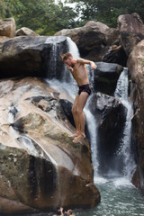 a man jumping off a cliff into the water