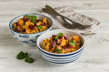 lentil with sausage and vegetables in pot on rustic background, top view
