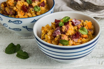 lentil with sausage and vegetables in pot on rustic background, top view
