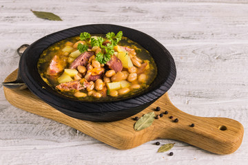 Bean, tomato, bacon and sausage stew with toasted bread