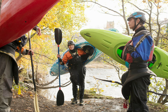 Male and female kayakers carrying kayaks on banks of  River Dee