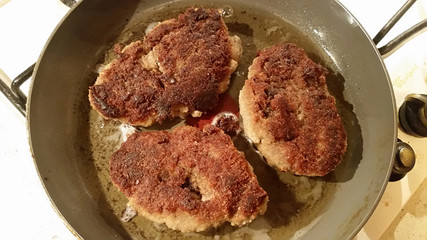 Fresh appetizing meat schnitzel fried in a pan in hot oil