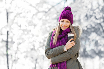 Young woman with coffee cup on snowy winter day