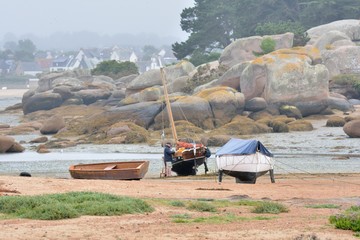 Un marin rénove son voilier à marée basse en baie de Sainte-Anne à Trégastel. Bretagne