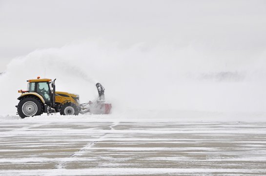 large tractor with snow plow at work during a winter storm