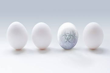 An illustration of three white eggs and a glassy transparent egg with water bubbles and biohazard sign on the grey background. Concept illustration, which shows sick and unhealthy egg among others.