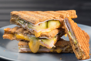 Pile of grilled sandwiches with cheese and ham.