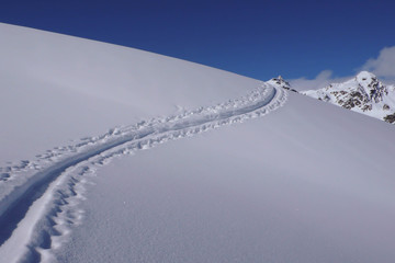 ski tracks in the snow in the Swiss Alps on a clear day with blue sky