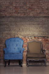 Two antique chairs against a grungy brick wall