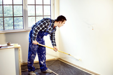 Worker house painter painted the walls in yellow