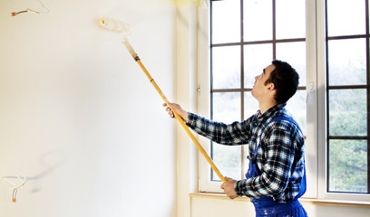 Worker house painter painted the walls in yellow