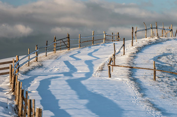 Fence pastures on a hill at sunset against the sky. A fabulous winter landscape.