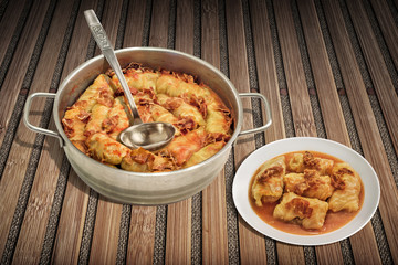 Plateful Of Cabbage Rolls Stuffed With Minced Meat Cooked In Tomato Sauce With Smoked Ham Slices In Stainless Steel Saucepot Set On Rustic Bamboo Place Mat 