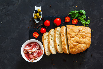 ciabatta, bacon, tomatoes on a black background. top view. idea for breakfast