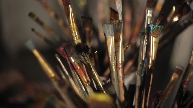 Various paintbrushes soiled with paints closeup