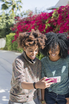 Smiling female friends using smartphone outdoors