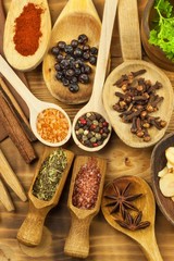Various kinds of spices on the kitchen table. Seasoning food. Sales of exotic spices. Advertising on spices. Powder spices on spoons in wooden table background.
