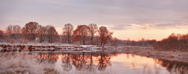Foto op Plexiglas Bewolkte en zonnige herfst dageraad. Eerste sneeuw op de herfstrivier. Oa © NemanTraveler