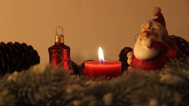 Weihnachtsmann neben brennender Kerze mit Weihnachtsschmuck