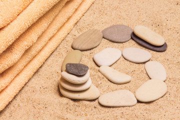 Fototapeta na wymiar Towel with pebbles on the sand