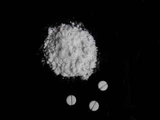 Obraz na płótnie Canvas Cocaine drug powder pile and pills on black background