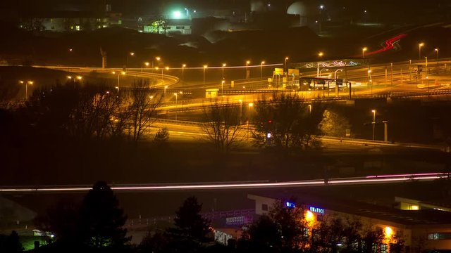 Time lapse of a city at night, with trails of the machines lights and smoke of factories. Time lapse di una citta di notte con scie di luci delle macchine e fumo delle fabbriche