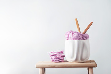 Balls of cotton yarn in pink with crocheted afghan squares