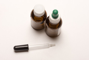 Studio image of clear glass pipette arranged with brown medicinal bottles