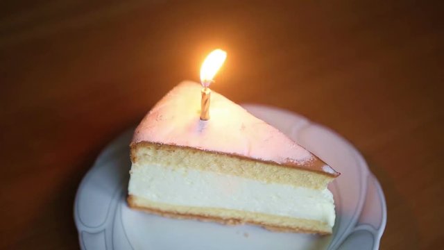 candle on slice of cake is burning fast until it goes out
