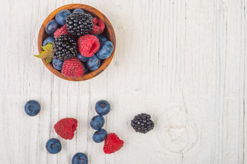 Blueberries and raspberries bowl on wooden table , top view