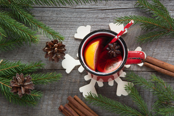 Christmas and festive mulled wine in a red mug with spices, cinnamon, star anise, cone, fir branch on a rustic wooden table. Christmas composition. Top view.