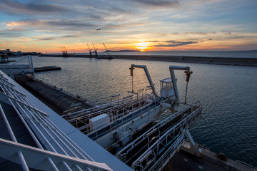 une digue devant le port de Marseille, au coucher de soleil, depuis les terrasses du port