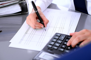 Bookkeeper or female financial inspector  making report, calculating or checking balance. Internal Revenue Service checking financial document. Audit concept.