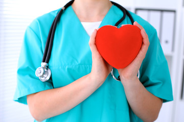 Female surgeon doctor with stethoscope holding heart.