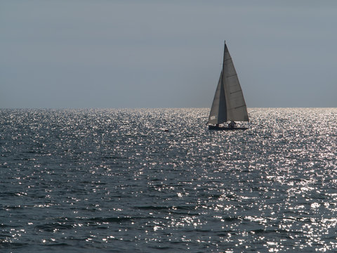 small sailboat sailing in a sparkling sea