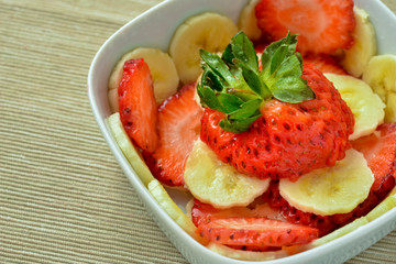 Bowl with strawberries and banana slices in natural light
