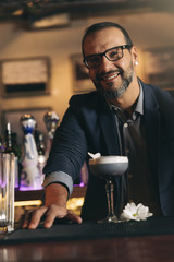 Barman is making cocktail at night club.
