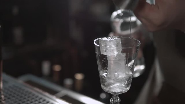 Alcohol flow in a glass with ice. Vodka pouring