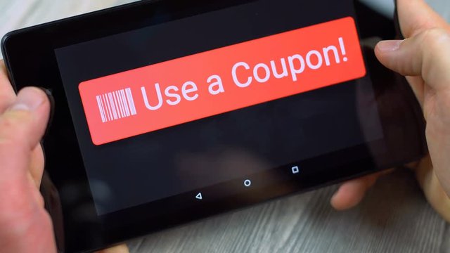 Man holding a tablet computer and pressing a big red Use a Coupon button