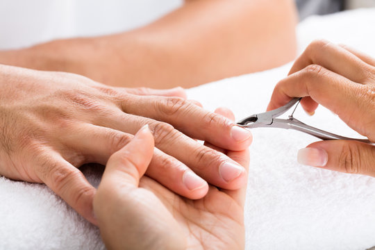 Manicurist Cutting Off The Cuticle From The Person's Fingers