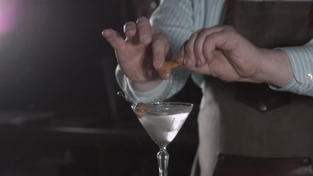Barman at work, preparing cocktails. Pouring margarita to cocktail glass. concept about service and beverages. Olive vermouth.