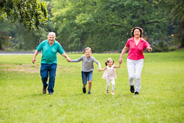 Fototapeta premium Grandparents And Grandchildren Running In Park