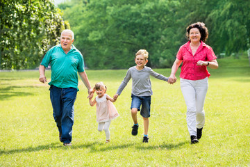 Grandparents And Grandchildren Running In Park